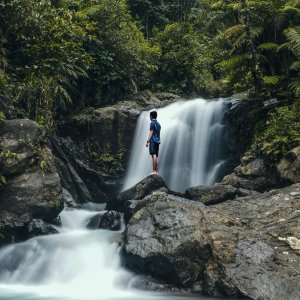 man standing on rocks with waterfalls background photo