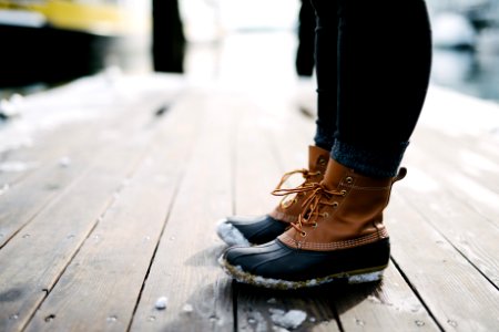 person wearing brown-and-black leather duck boots standing on brown wooden dock photo