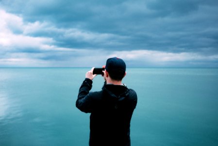 men's black hoodie in front of teal sea photo