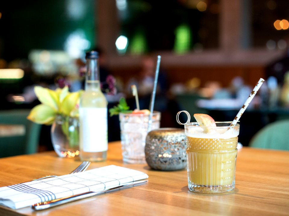filled liquid in glass beside fork and table knife near bottle on table