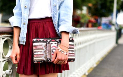 woman holding clutch bag standing beside white bridge photo