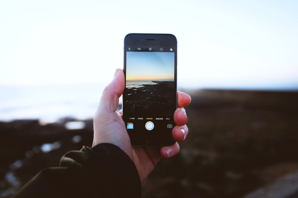 person taking photo of landscapes using iPhone during daytime