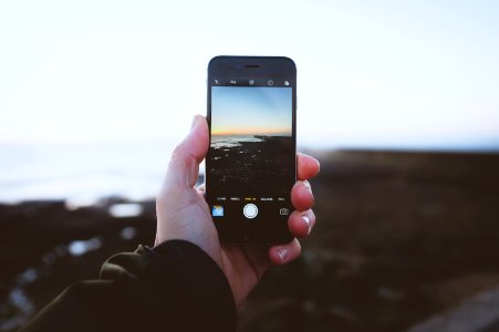 person taking photo of landscapes using iPhone during daytime photo