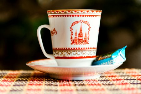 selective focus photography of white-and-red teacup on saucer with blue labeled food pack photo