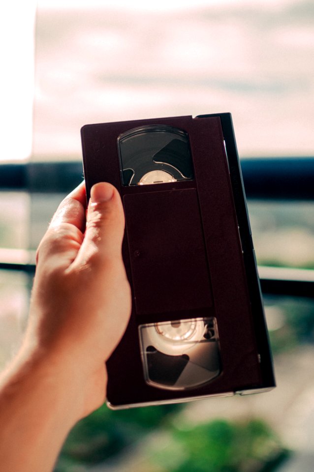 person holding black VHS tape