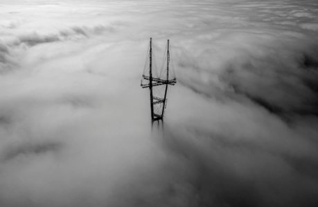 grayscale photo of tower surrounded by clouds photo