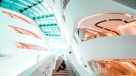 sitting woman on stairs inside white concrete building photo