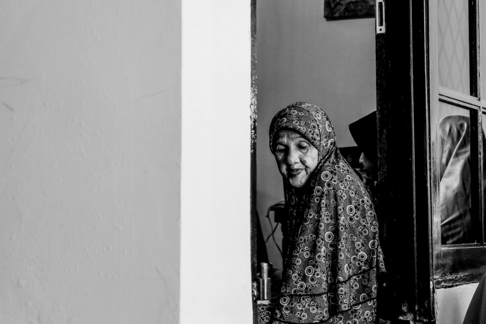 grayscale photo of woman between doors