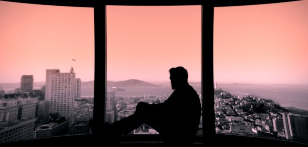 silhouette of person sitting on building's window photo