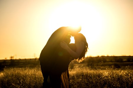 man and woman kissing on grass field during day time photo