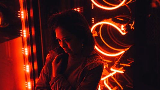 woman in gray coat standing at the front of red lights