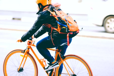 closeup photo of person riding a orange bicycle photo