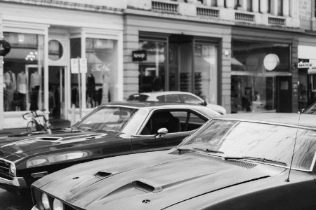 greyscale photography of cars on road beside buildings photo