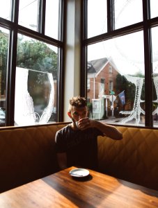 man sitting on brown sofa while drinking photo