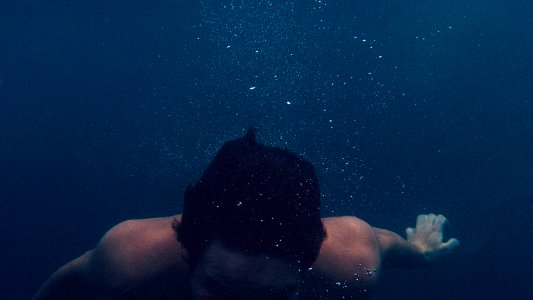 man submerged on body of water photo