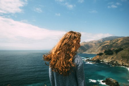 woman standing facing the ocean during daytime photo