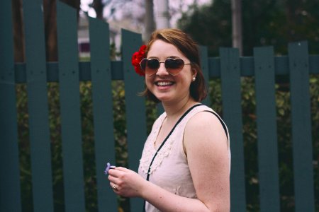 woman standing while smiling beside blue wooden fence photo