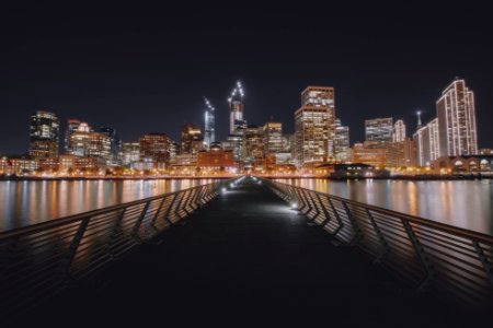 single perspective photography of foot bridge and cityscape by water photo