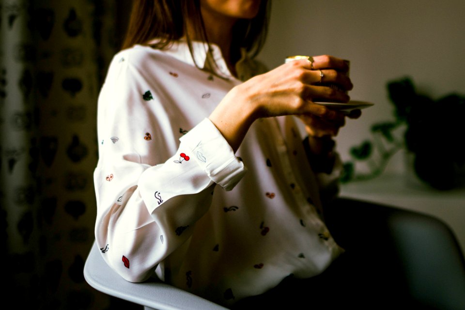 woman in white long-sleeved collared shirt holding teacup
