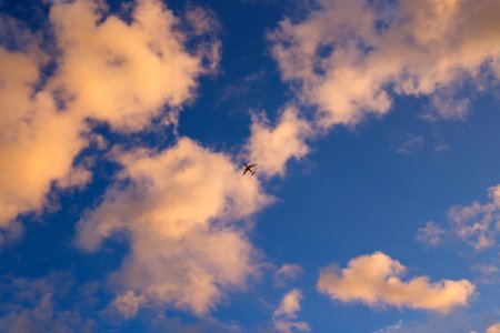 silhouette of plane flying under white and blue sky during daytime photo