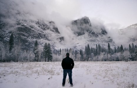 man in black jacket standing on snow covered ground photo