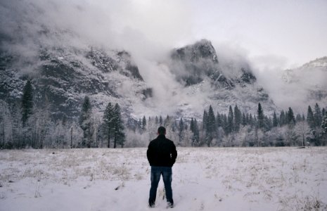 man in black jacket standing on snow covered ground