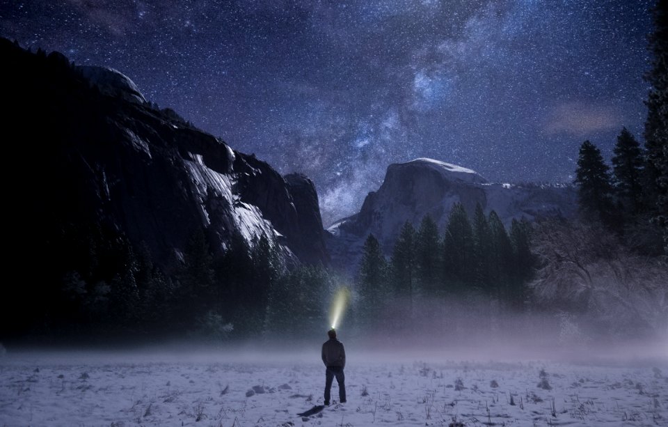 person wearing headlamp facing towards snow mountain