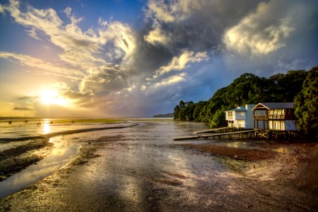 photo of white and brown wooden house beside seashore during sunrise photo