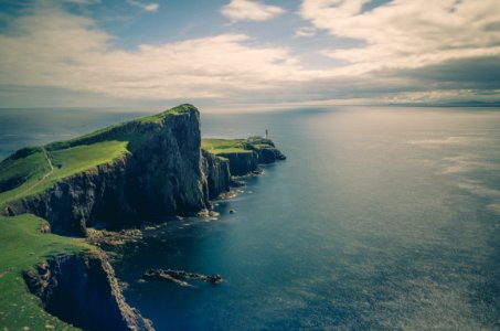 sea and rock cliff with grasses under cloudy sky photo