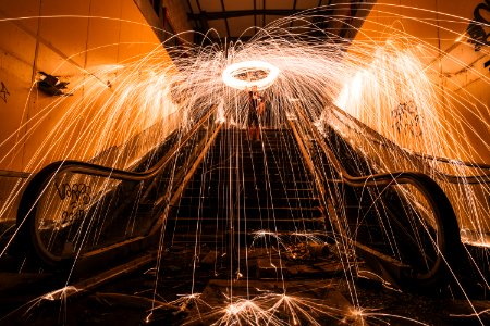 steel wool photography of man standing on stairs photo