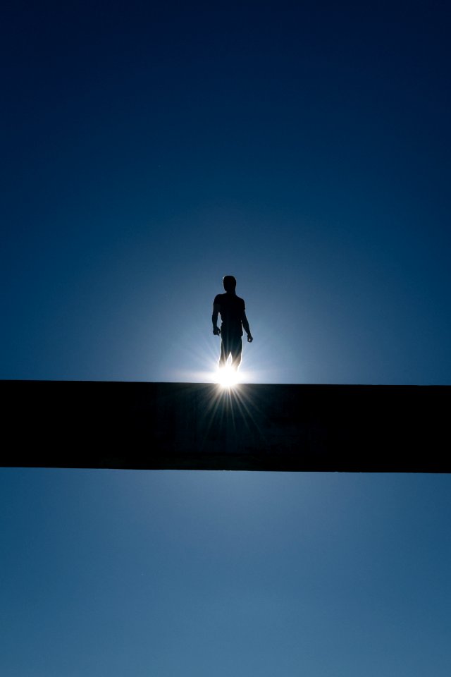 silhouette of man standing on bridge