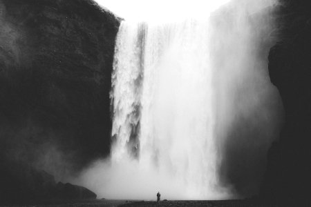 grayscale photo of man facing waterfalls