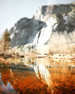 reflection of rock cliff on calm river water photo