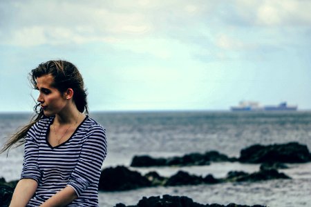 focus photography of woman in black and white striped V-neck elbow-sleeved shirt near sea during daytime photo