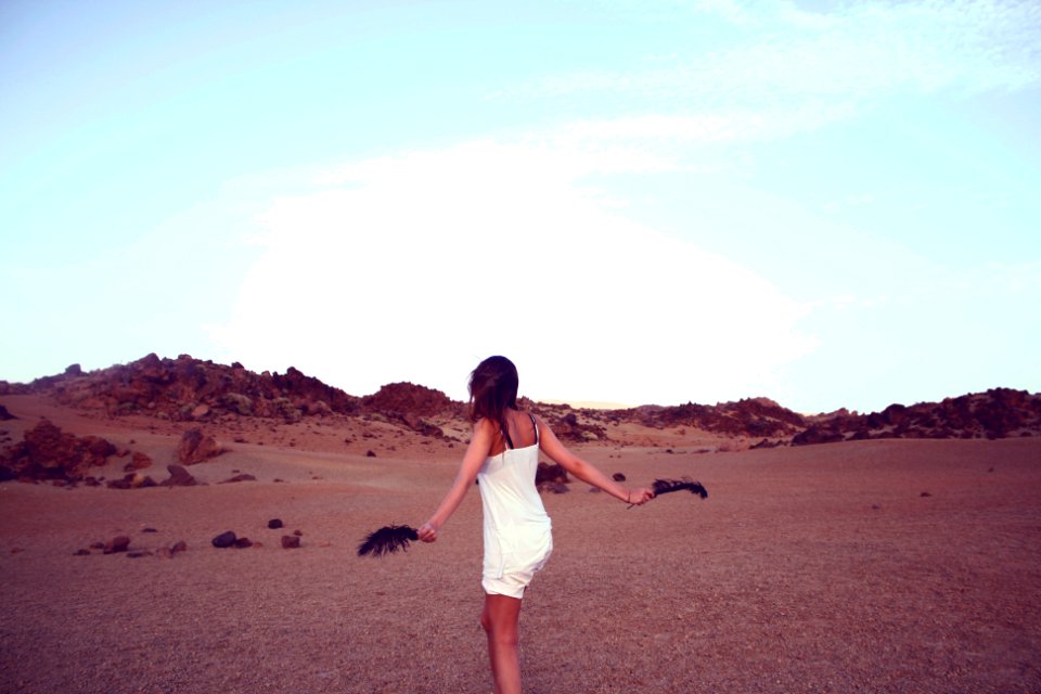 woman in white dress holding black feathers