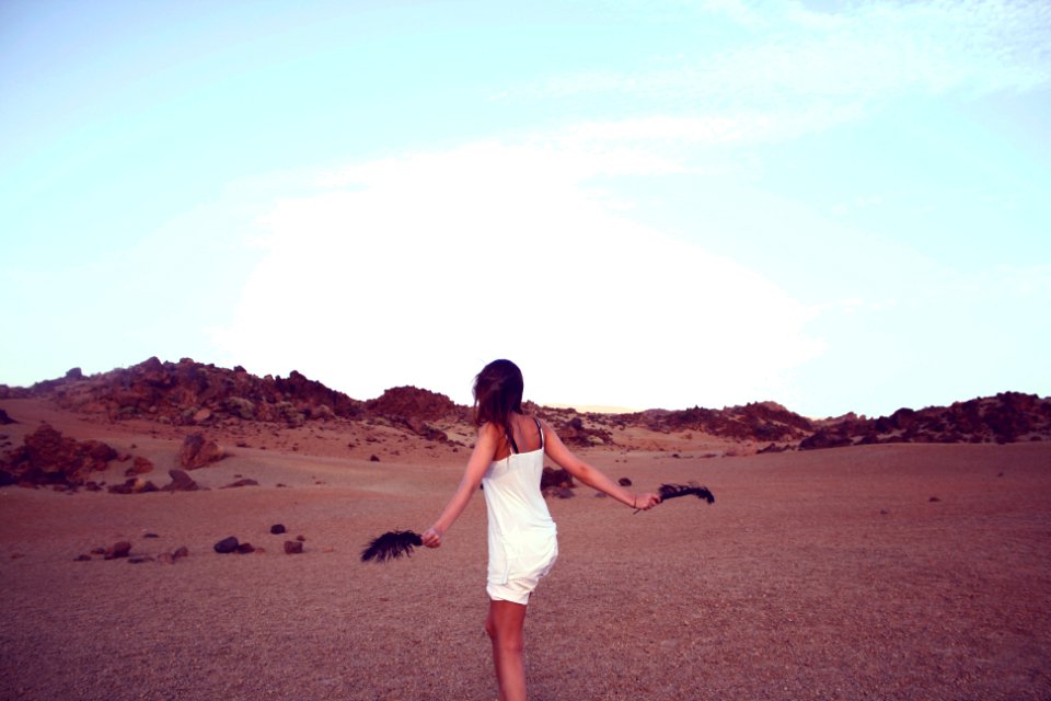 woman in white dress holding black feathers photo