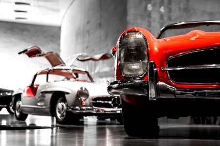 two vintage cars beside gray concrete wall photo