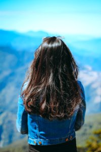 woman wearing blue denim jacket standing near mountain photo