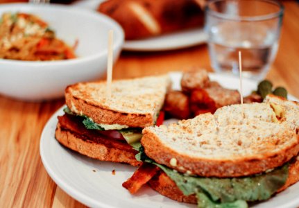 two sliced of sandwich on plate near bowl and drinking glass photo