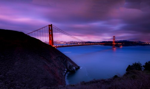 red bridge below body of water during sunset photo