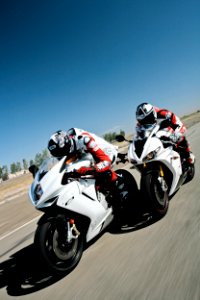 two people riding sports bikes on gray asphalt road during daytime photo