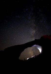 silhouette photo of person stand on rocks during nighttime photo