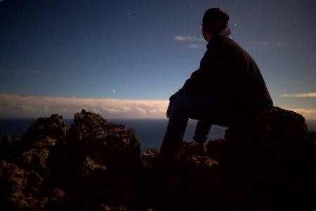 person sitting on rock looking at sky photo