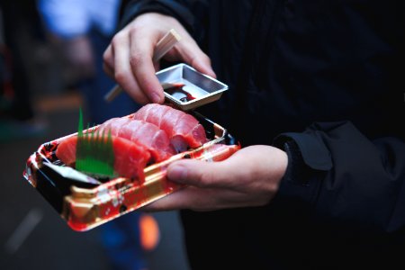 person holding tuna sashimi photo