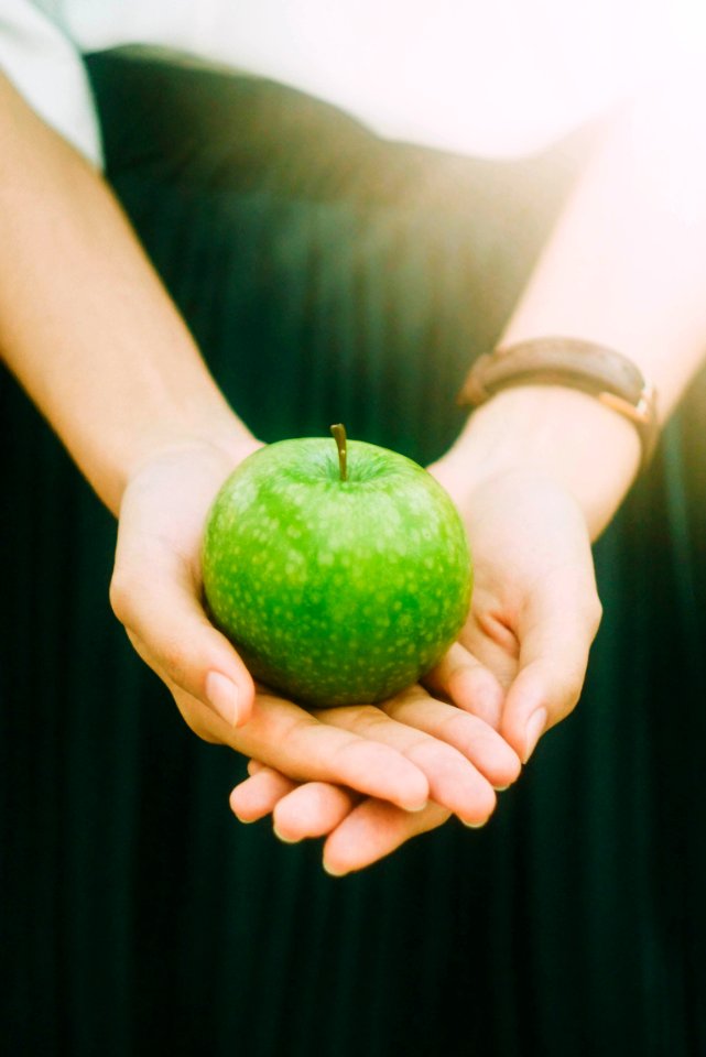 person holding green apple
