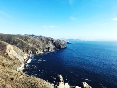 cliff beside ocean under clear blue sky during daytime photo
