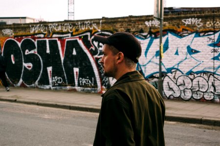 man walking on asphalt road near wall with graffitis photo