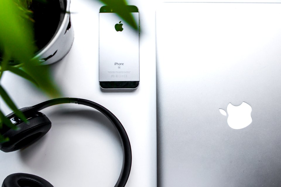 space gray iPhone SE beside headphones and silver MacBook