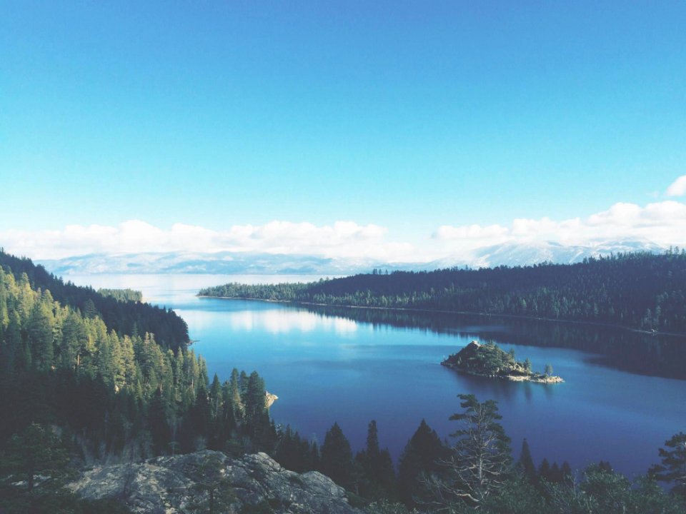 lake surround by mountains and trees under blue sky
