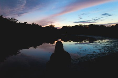 silhouette of person sitting near body of water photo